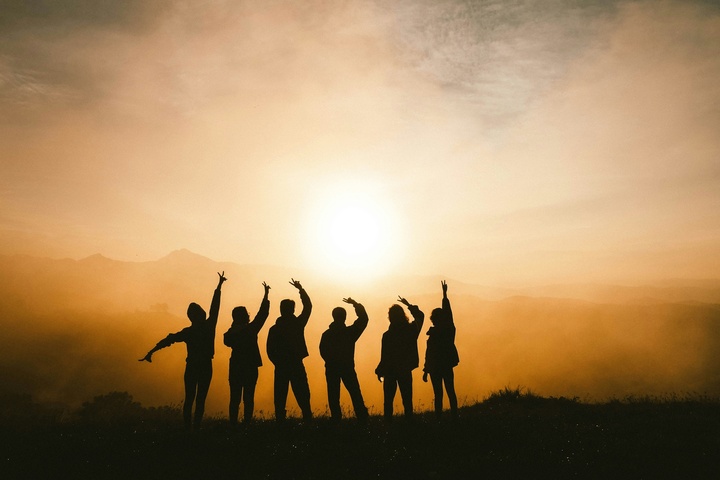 Silhouettenfoto von sechs Personen auf Berggipfel im Sonnenuntergang